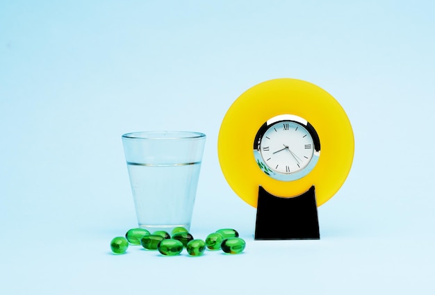 Medical pills glass water and alarm clock on a blue background concept medicine and treatment