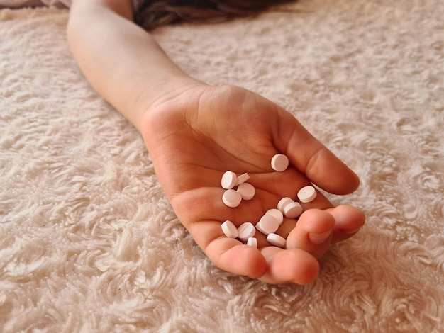 Medical pills in hands of child in bed