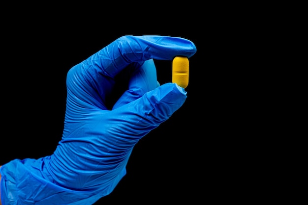 Medical pills on isolated black background with reflection in hand