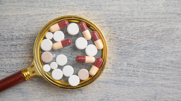 Medical pills with a magnifying glass on the table