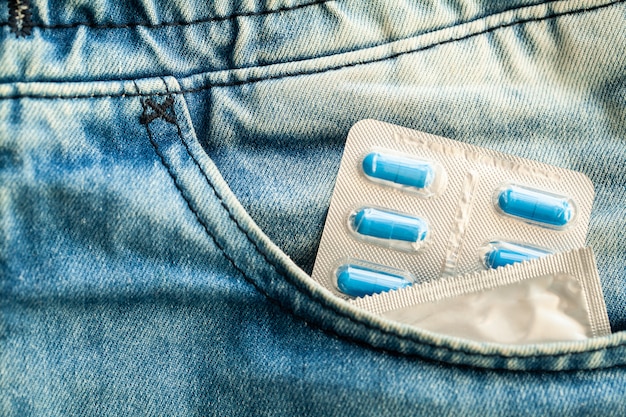 Medical potency pills and condom in pocket jeans.