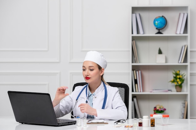 Medical pretty cute doctor in white lab coat and hat with computer talking to patient