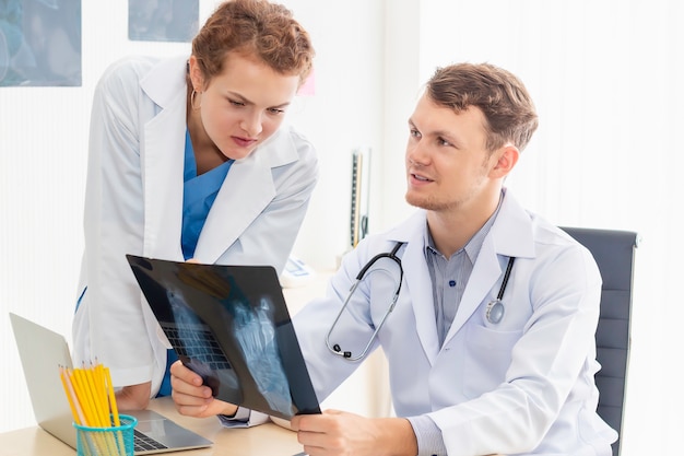 Photo medical professionals caucasian man holding xray and conversation about patient with young doctor woman.