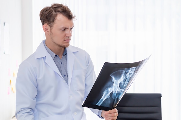 Medical professionals caucasian man holding xray in the hopital room.