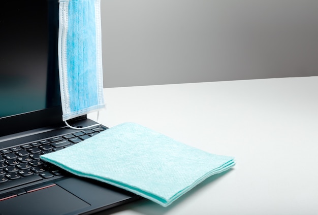 Medical protective mask on laptop work space. napkin cloth laptop keyboard for cleaning surfaces