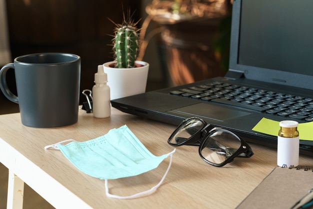 Medical protective mask on office table. Coronavirus spread prevention concept. Stay at home