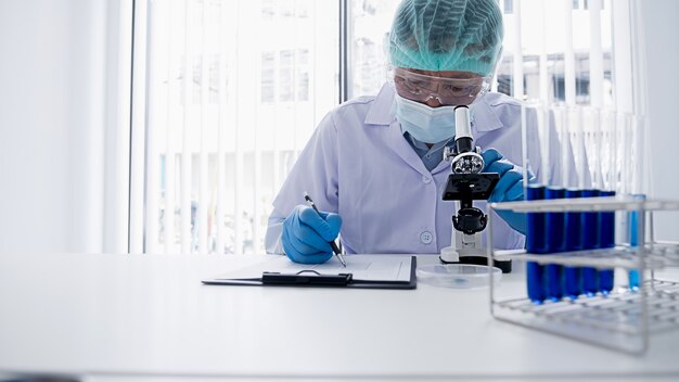 Foto ricercatore medico o scientifico o medico che guarda una provetta di soluzione chiara in un laboratorio