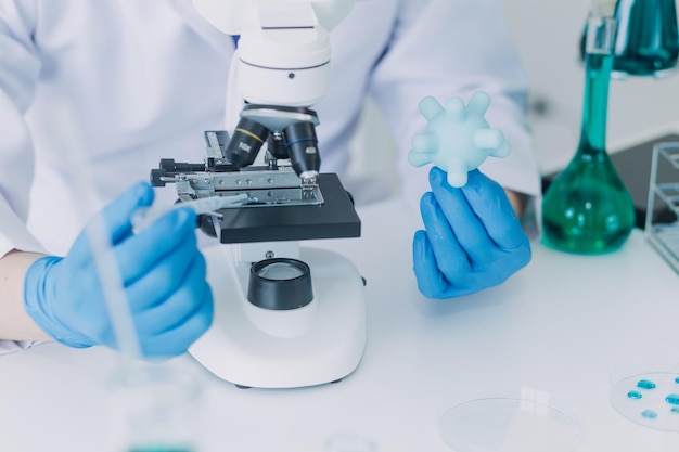 Medical or scientific researcher researching and experimenting Multicolored solution vial and microscope In the laboratory or in the laboratory by wearing blue gloves and white clothing completely