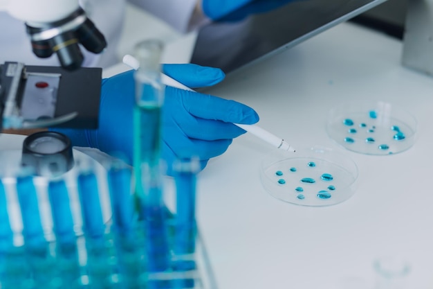 Medical or scientific researcher researching and experimenting Multicolored solution vial and microscope In the laboratory or in the laboratory by wearing blue gloves and white clothing completely