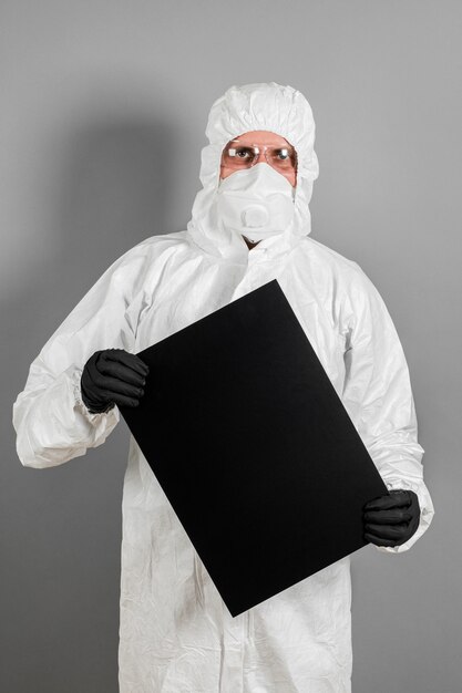 A medical scientist or policeman in protective clothing holds an empty banner for your advertisement. The concept of health and crime.