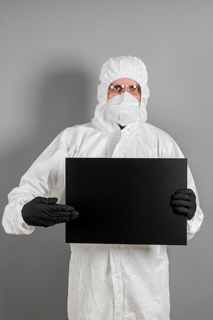 A medical scientist or policeman in protective clothing holds an empty banner for your advertisement. The concept of health and crime.