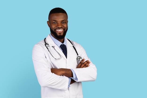 Medical services handsome black male doctor in uniform posing with folded arms