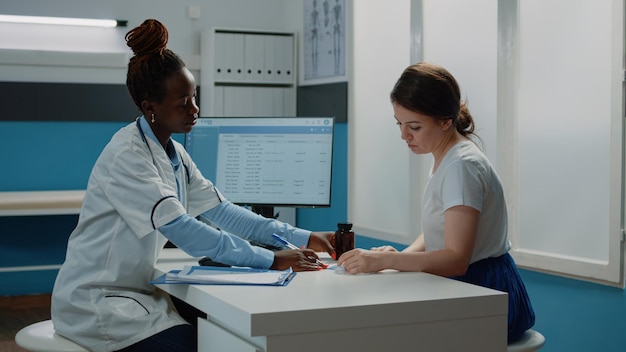 Medical specialist giving bottle of pills and checkup paper to patient for healthcare treatment. Doctor preparing prescription medicine and flask to cure disease after consultation.