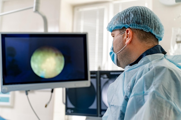 Medical specialist in modern operating room. Doctor performs a surgery and looking on the process on the monitor.