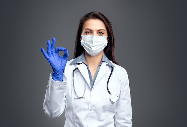 Medical specialist in protective mask showing okay gesture