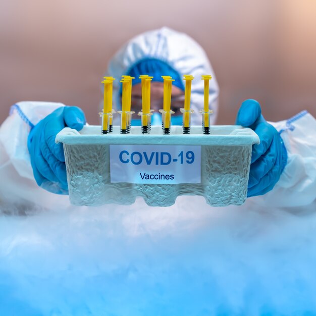 写真 冷凍庫内にcovid-19ワクチントレイを配布する医療スタッフ。ヘルスケアと医療の概念