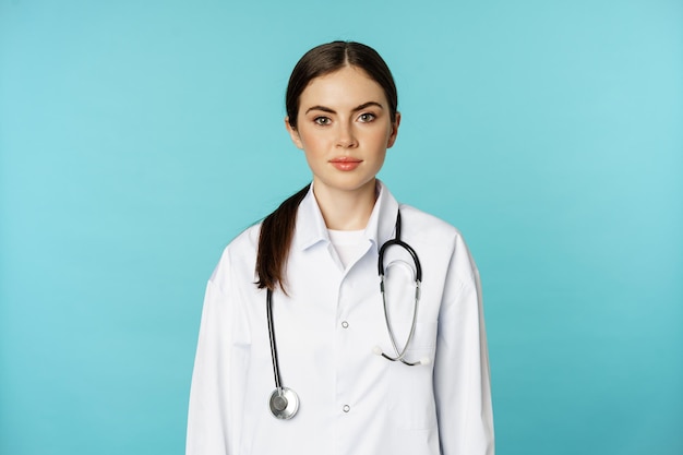 Медицинский персонал и врачи представляют молодую улыбающуюся женщину-врача в белом халате и ст...