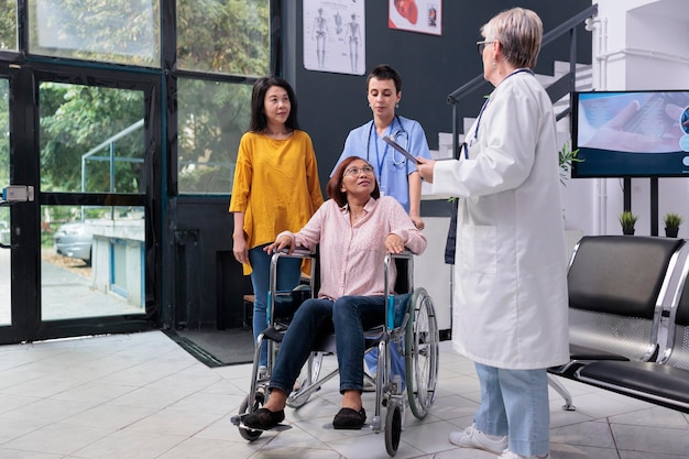 Medical staff talking with injured patient before medical\
consultation in hospital waiting area. physician doctor giving\
medical advice to asian woman during rehabilitation exam. medicine\
support