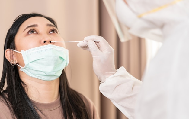 Medical staff with PPE suit test coronavirus covid-19 to Asian woman