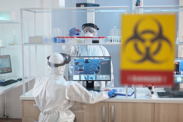 PPE 슈트를 입은 실험실 위험 구역에서 일하는 의료진