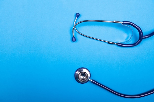 Medical stethoscope on blue background in studio photo. Top view