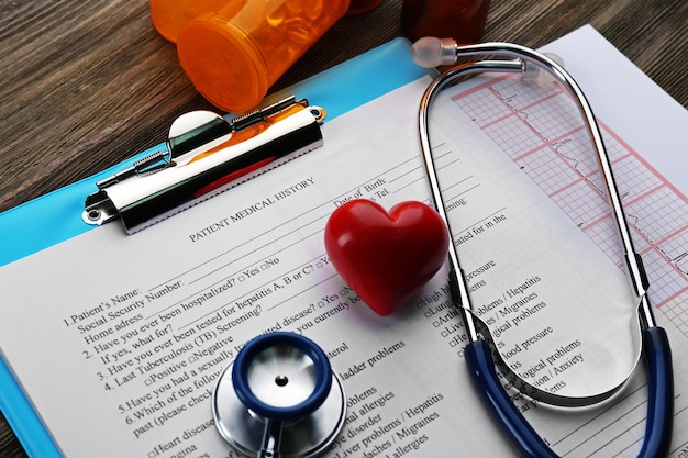 Medical stethoscope clipboard pills and plastic heart on the table