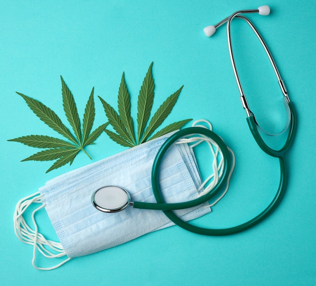 Medical stethoscope, disposable mask, latex sterile gloves and green hemp leaf