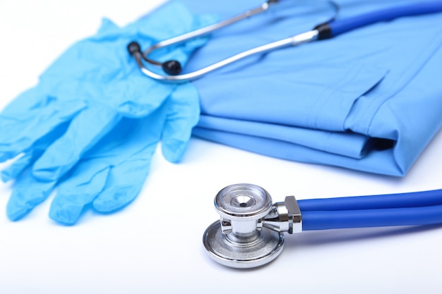 Medical stethoscope and gloves lying on blue uniform doctor close up. 