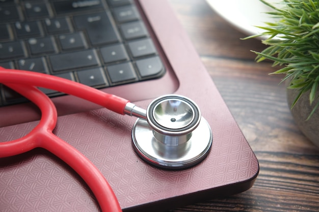 Medical stethoscope on laptop on wooden table