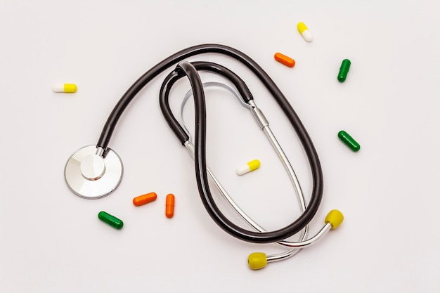 Medical stethoscope and pills isolated on white background