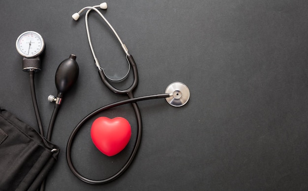 Medical stethoscope and sphygmomanometer on black background top view