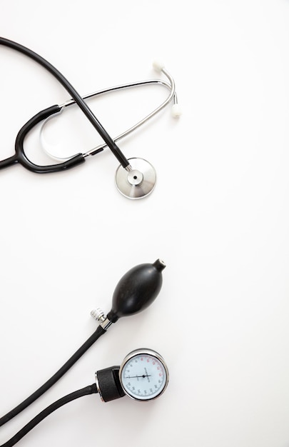 Medical stethoscope and sphygmomanometer on white background top view