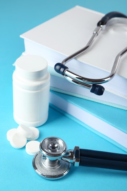 Medical stethoscope with books and tablet on blue background