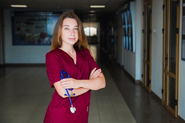 Medical student smiling at the camera at the university in Burgundy in a surgical suit. professional girl surgeon doctor.