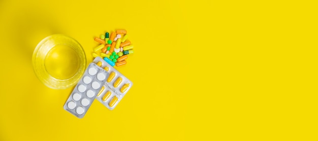 Medical supplies on a yellow background, pills water treatment mask virus. Selective focus