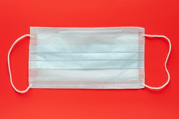 Medical surgical face mask on red background. World pandemic insurance, airborne diseases, SARS, influenza. Protective antivirus masks for human - cover mouth and nose. Concept of fight against virus.