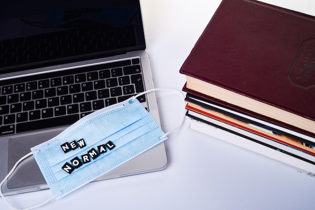 A medical or surgical mask on a stack of books. Quarantine and self-isolation concept