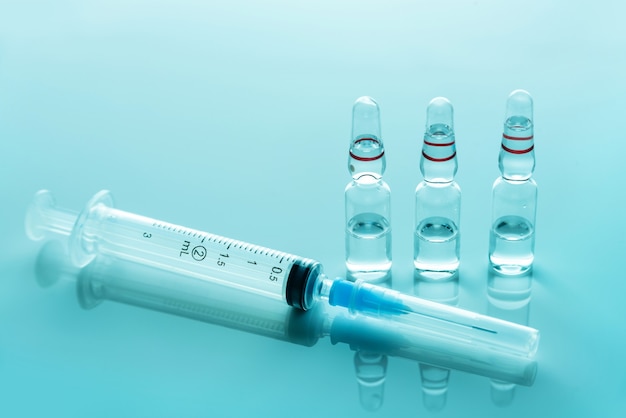 Medical syringe and glass ampoules with medicine close-up.