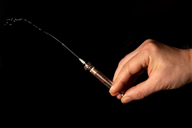 Medical syringe in man hand on black isolated background