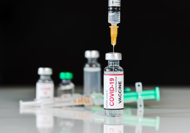 Medical syringe needle drawing Coronavirus (Covid-19) vaccine shot from a glass of bottle