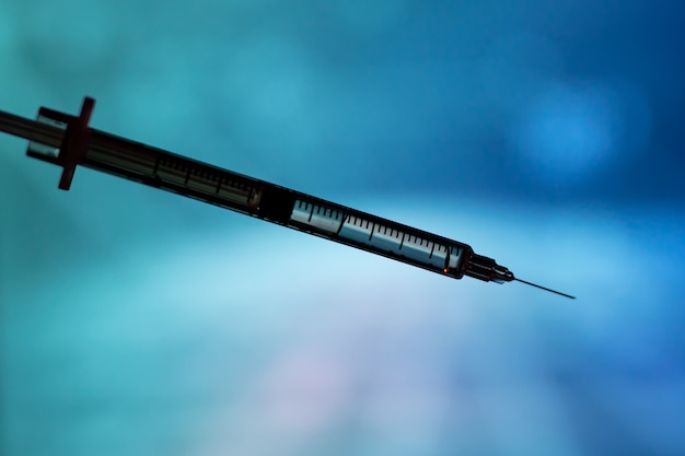 Medical syringe for a vaccine. Blue background.