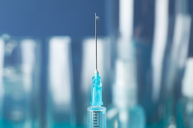 Photo medical syringe of vaccine, injection on blue. coronavirus protection. healthcare and medical concept