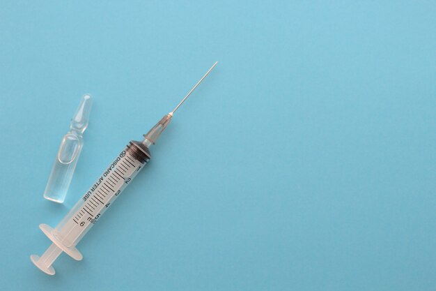 Medical syringe with ampoule on a blue background