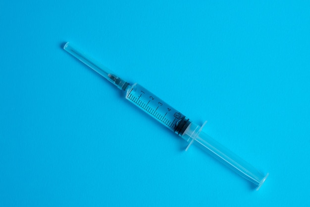 Medical syringe with vaccine on blue. Top view