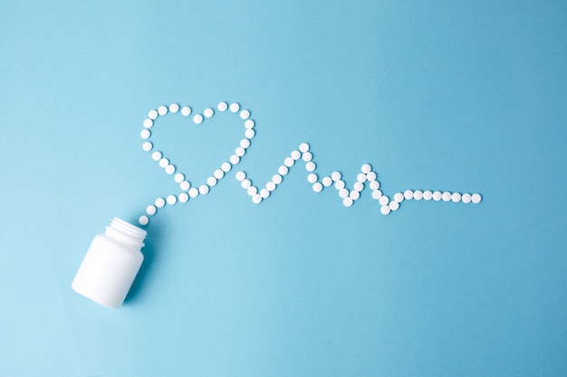 medical tablets in the form of a heart and cardiogram, capsules on a blue background. the concept of a healthy heart,