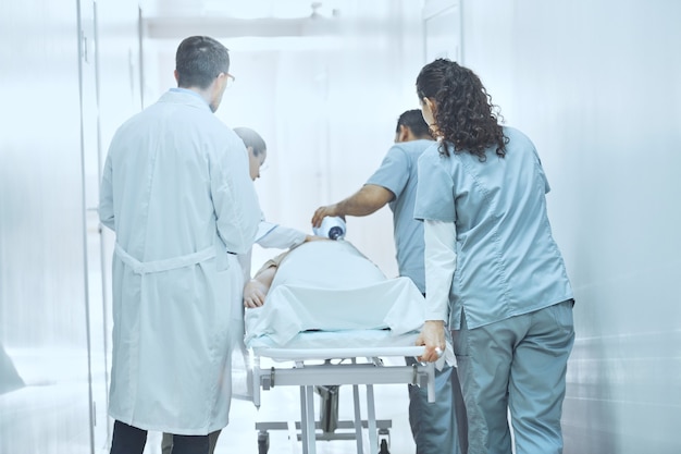 Medical team do CPR cardiopulmonary resuscitation to seriously injured patient with oxygen mask while push gurney stretcher bed to operating Room