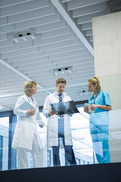 Medical team discussing over x-ray report in corridor