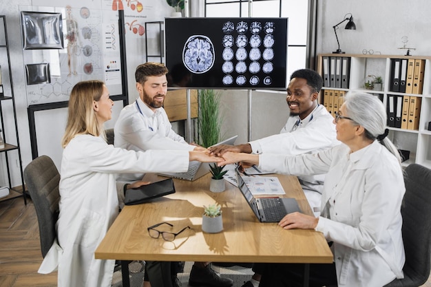 Medical team of doctors stacking hands together at clinic