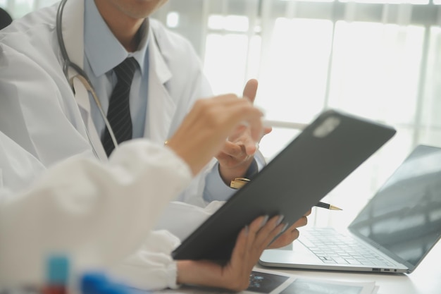 흰색 실험실 가운을 입은 의사들과 테이블에 앉아 수술용 수술복을 입고 환자 기록에 대해 논의하는 의료 팀 의학 의사의 작업 개념