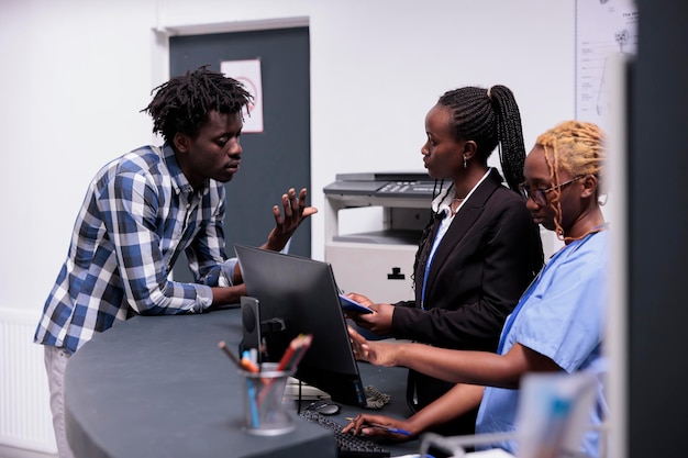 Medical team helping patient with appointment, having checkup visit consultation with specialist and waiting at reception counter. Nurse, doctor and receptionist talking to person with disease.